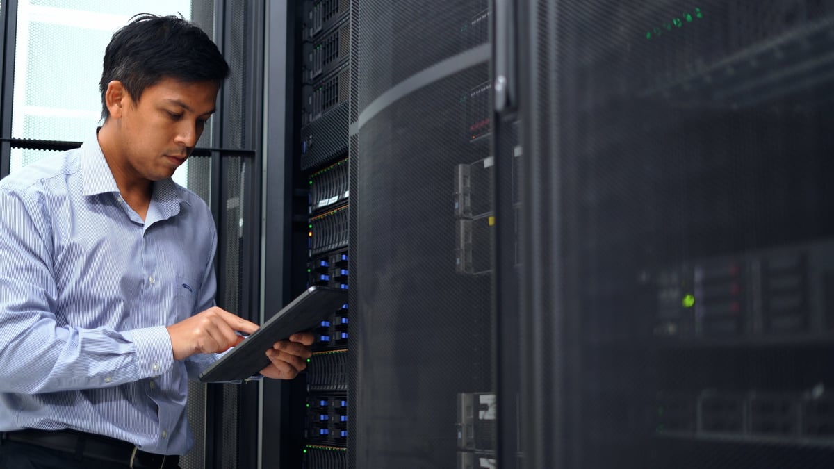 Technician using a tablet to check equipment in a server room